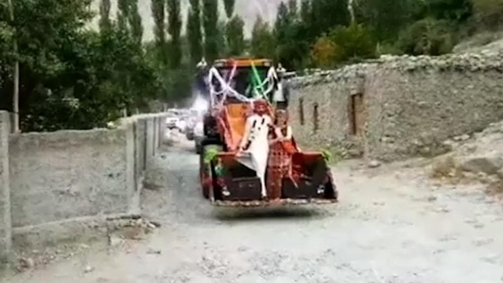 Newlywed couple in Pakistan arrive in village riding an excavator 