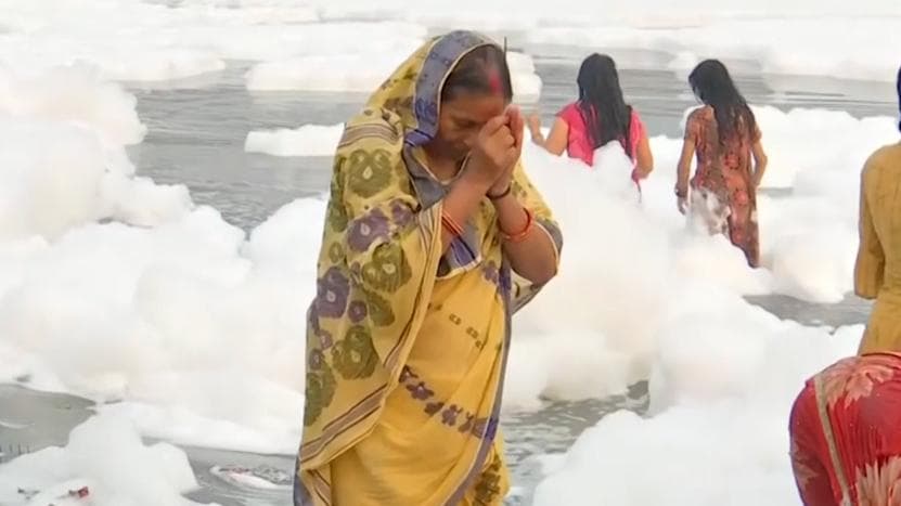 Chhath puja: devotees in Delhi take dip as toxic foam floats on Yamuna
